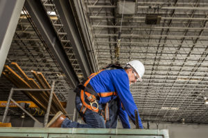 man wearing orange safety harness while working